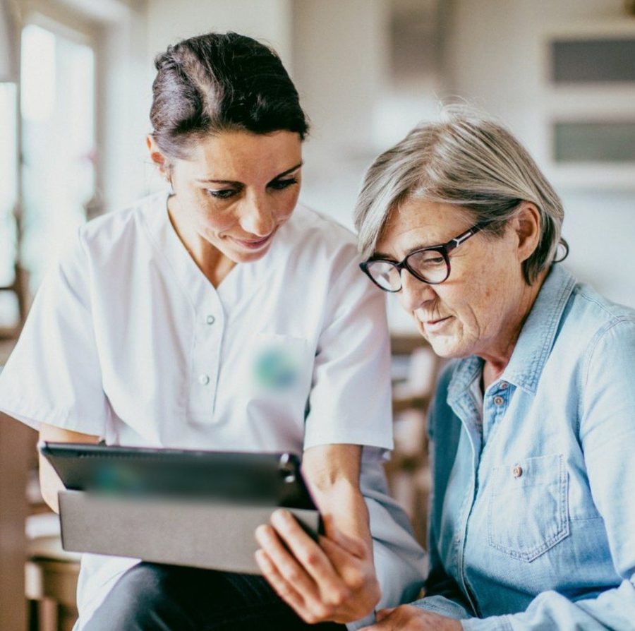 A carer helping an older woman use the tablet
